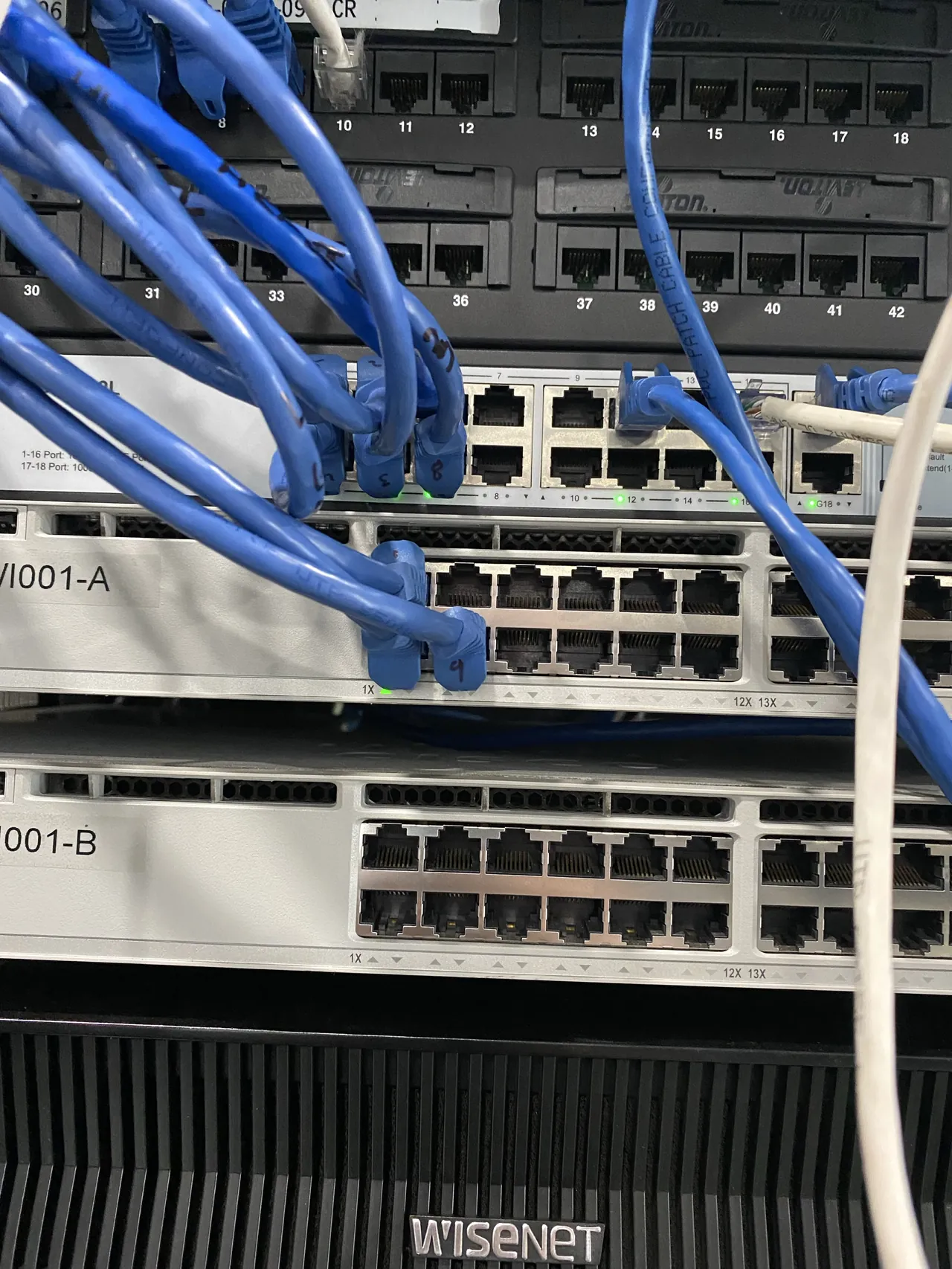 Structured wiring rack with patch panel and neatly dressed blue runs.